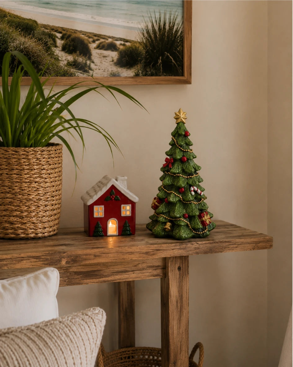 Lit ceramic red house tea light holder styled with pinecone and red berries