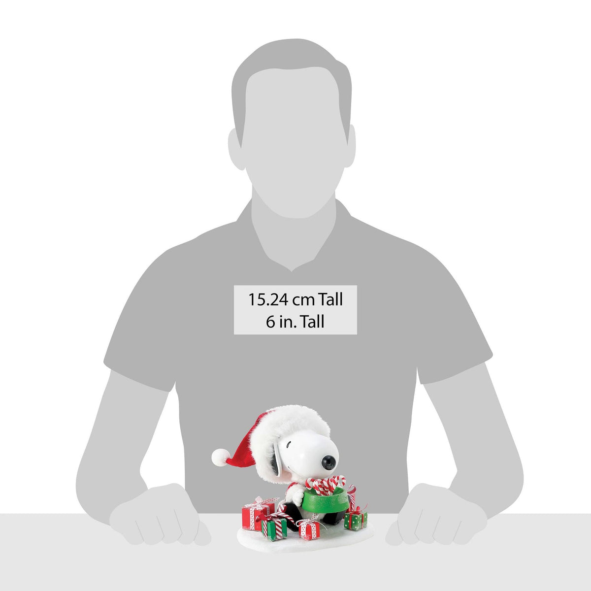 Size reference showing Snoopy Santa figurine beside a human silhouette; figurine stands 15.24 cm (6 inches) tall