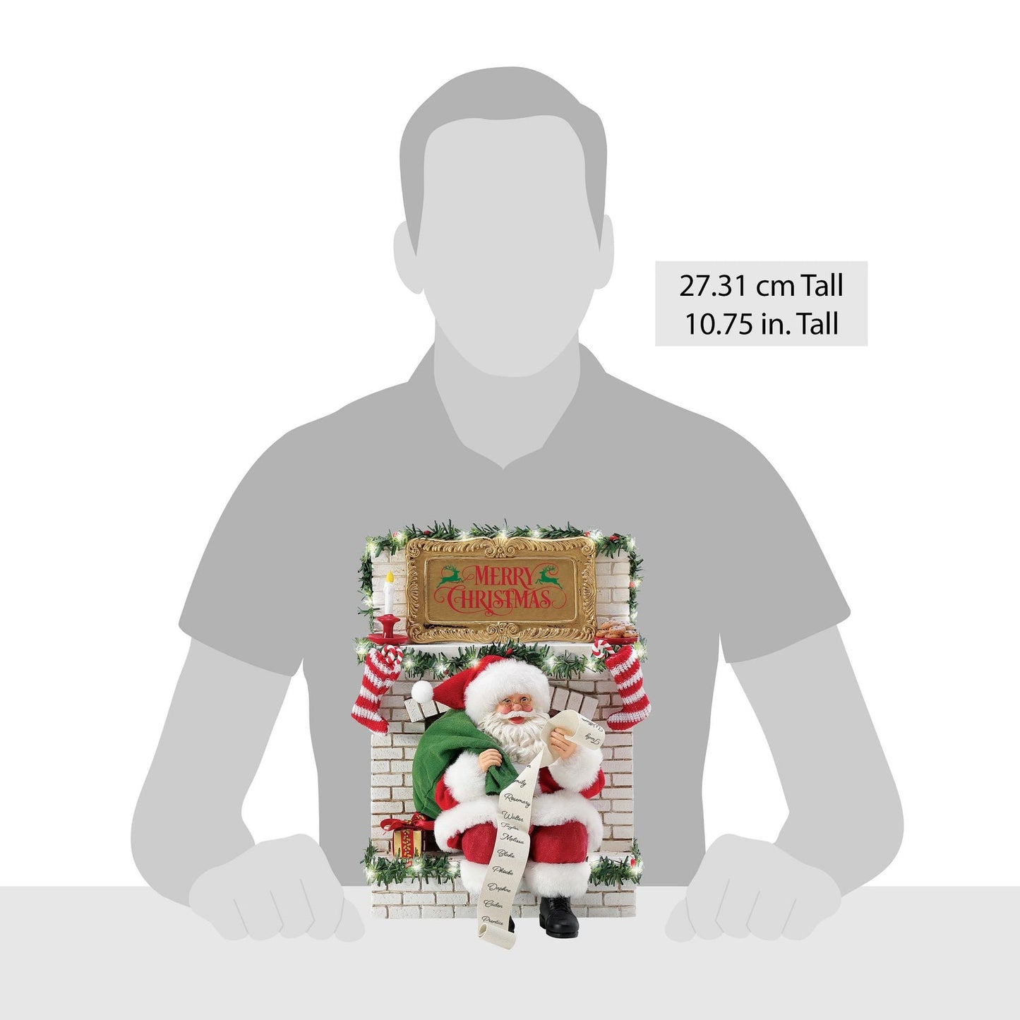 Santa-at-the-fireplace figurine set shown against a human silhouette for scale, 27.31 cm / 10.75 inches tall