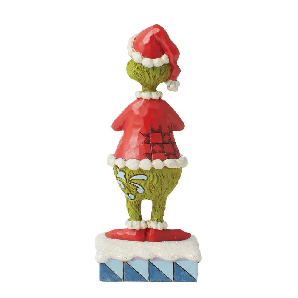 Rear view of Grinch figurine in Santa hat and red diamond-patterned coat, arms folded, snowy blue-striped base
