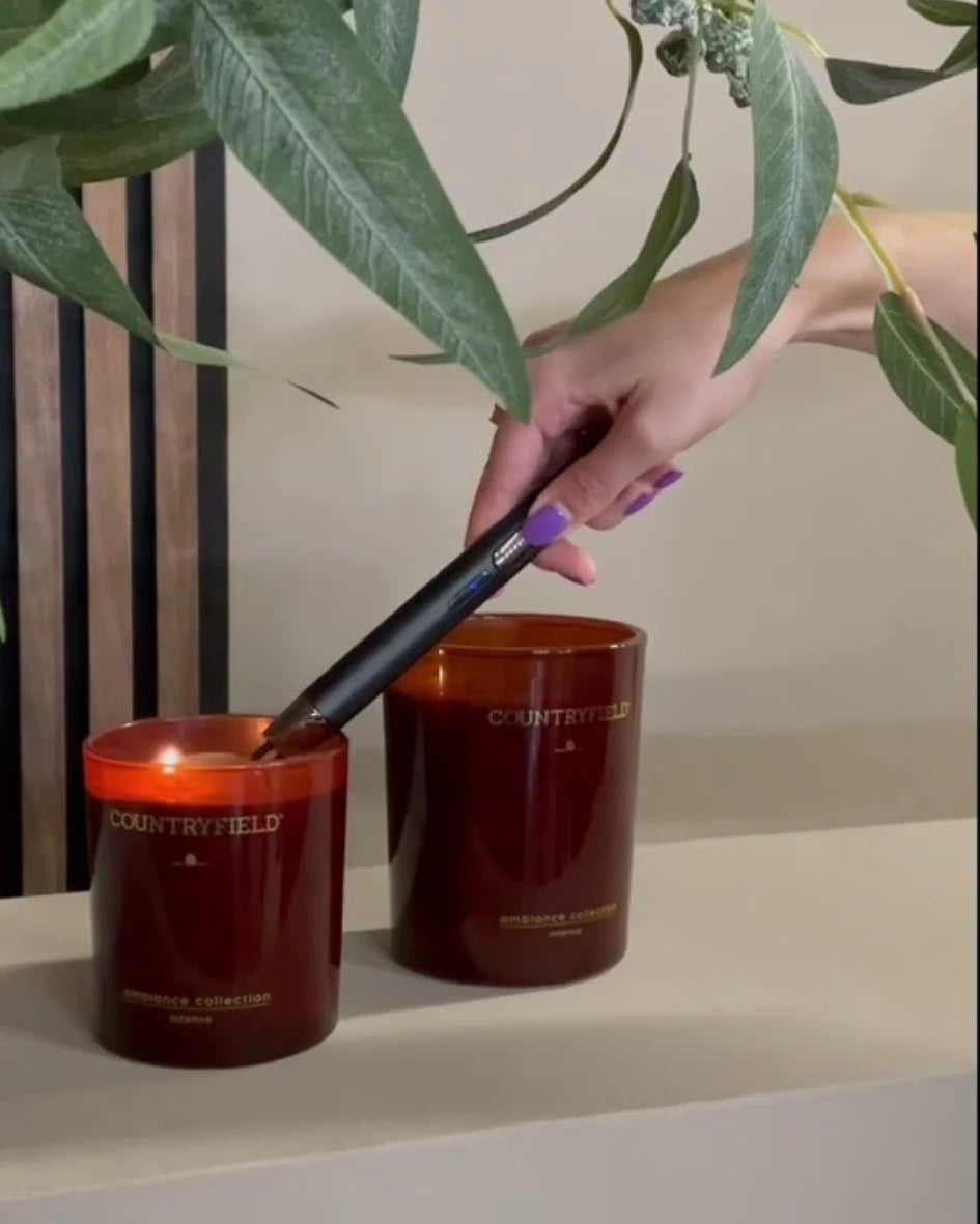 Arc lighter being used to light a Countryfield candle in a red glass jar