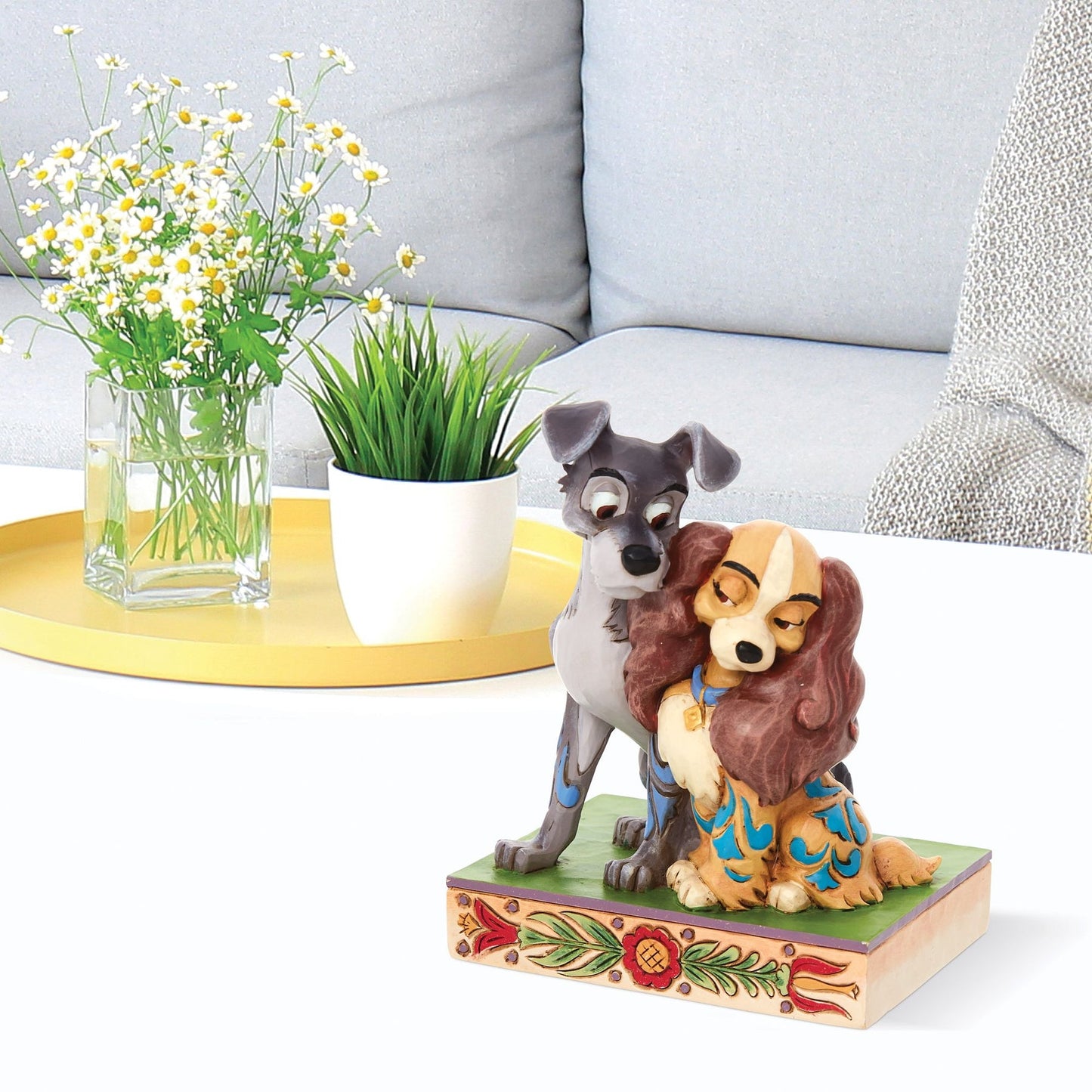 Lady and the Tramp figurine styled on a coffee table, Tramp nuzzling Lady on a floral painted base