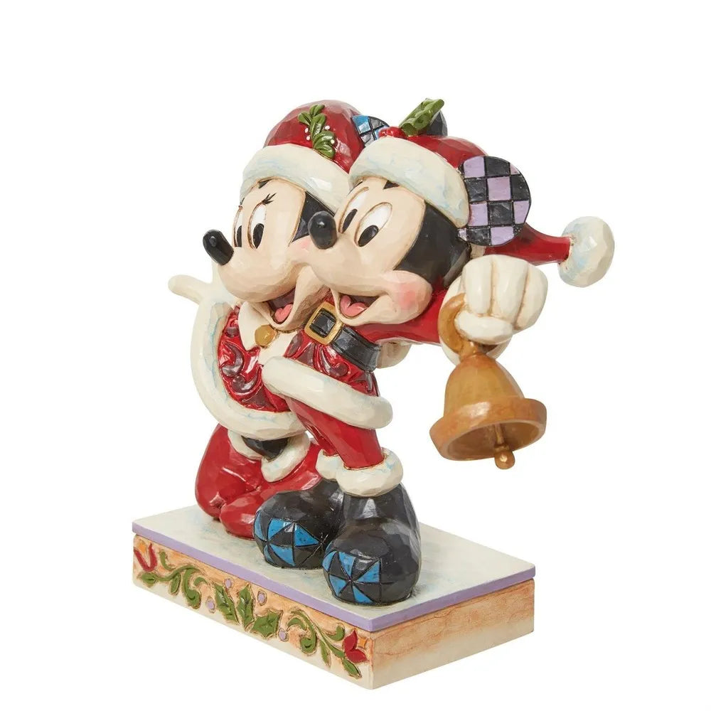Angled front view of Mickey and Minnie Mouse Santa figurines cheek to cheek, Mickey holding a gold bell, on a holly-detailed base