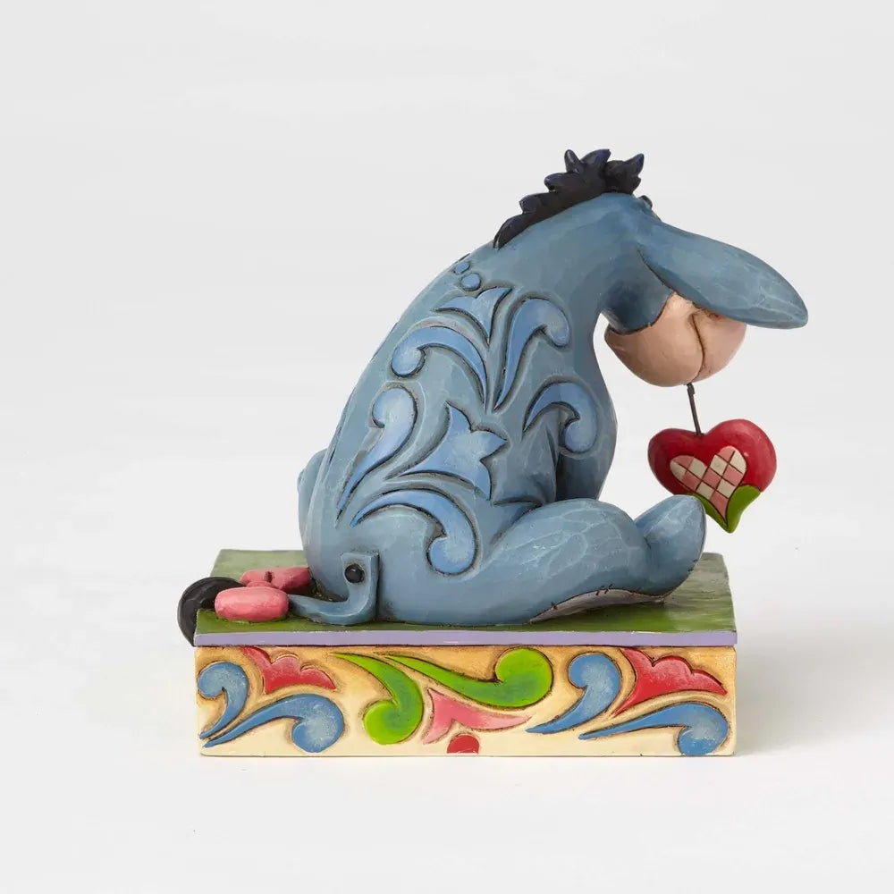 Eeyore figurine rear view showing blue scrollwork body detail, holding a red heart, on a colourful scrollwork painted base