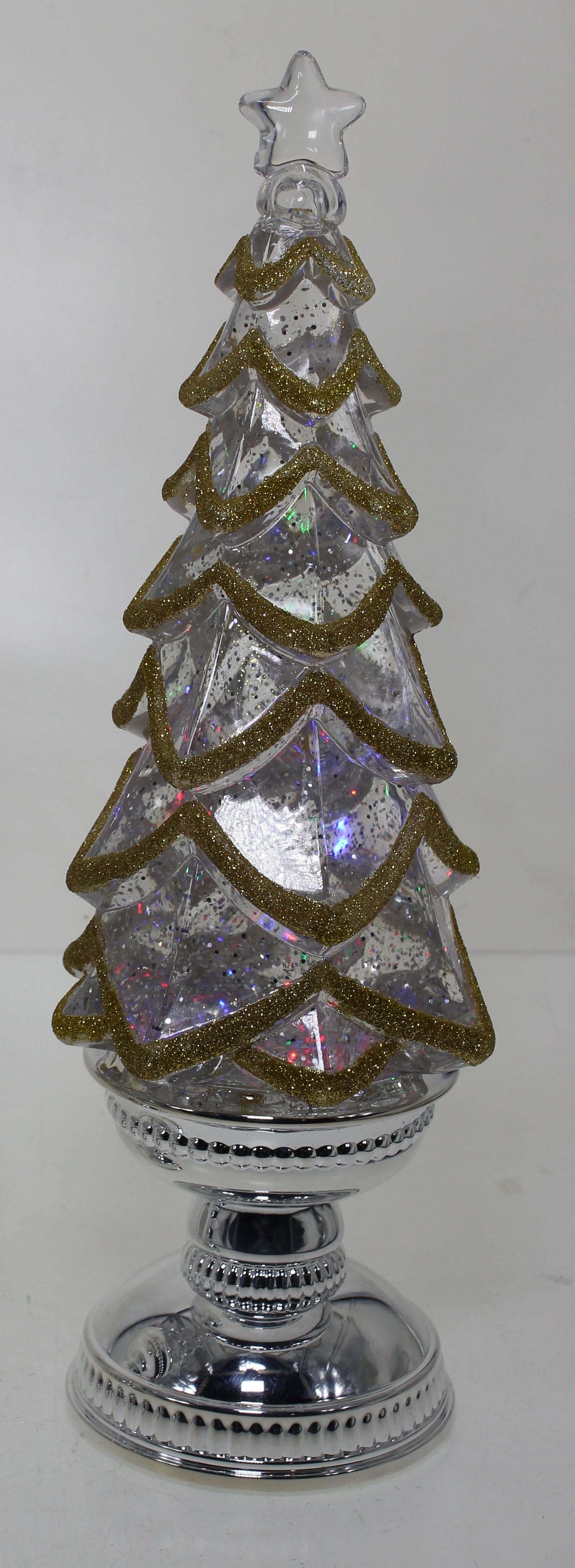 Decorative Christmas tree with a star on top, placed on a reflective surface.