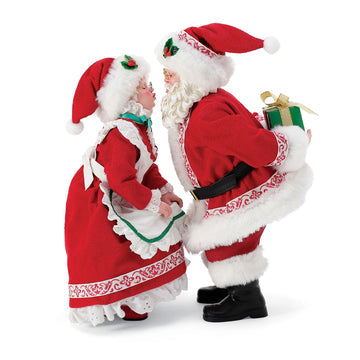 Side view of Santa and Mrs Claus figurine set, Santa holding a green wrapped present
