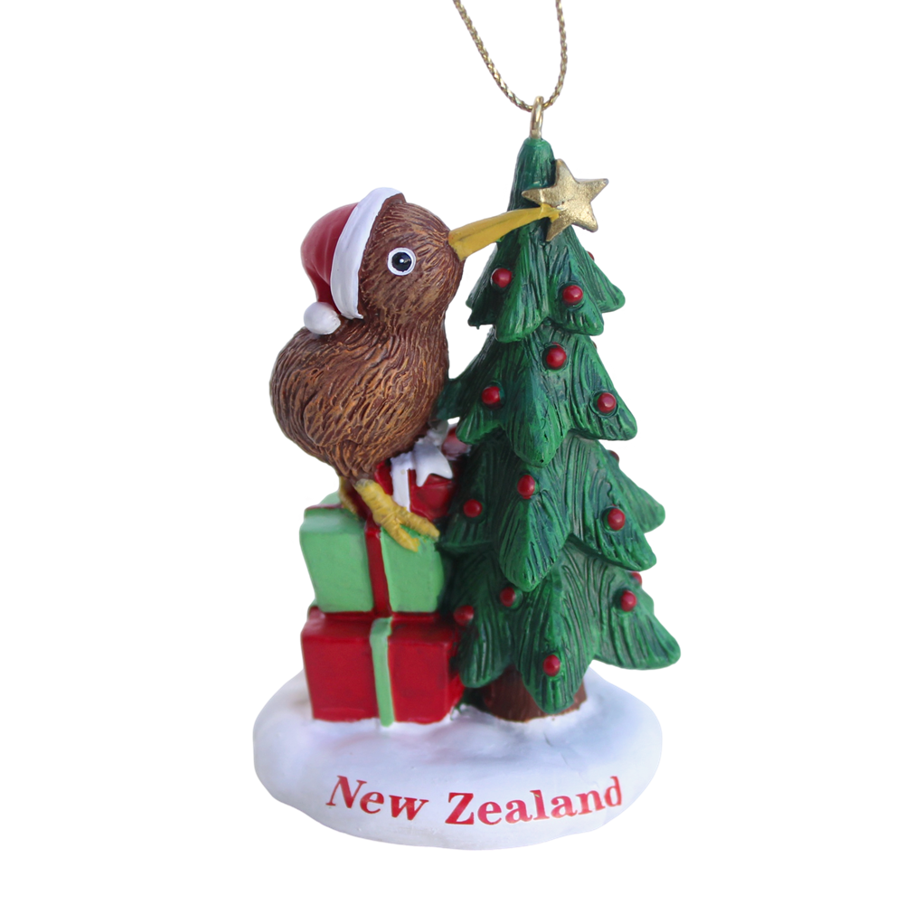 NZ kiwi bird in a Santa hat placing a star on a Christmas tree with gifts hanging ornament
