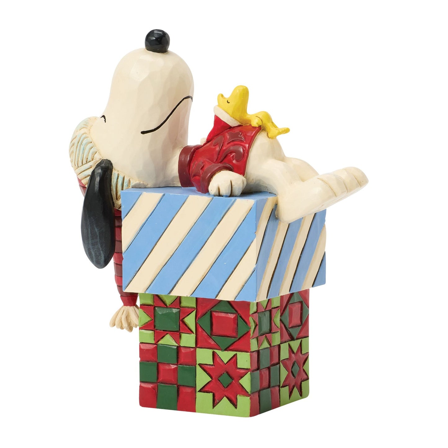 Angled view of Snoopy and Woodstock Christmas figurine, Snoopy resting on stacked blue stripe and red quilt-patterned gift boxes