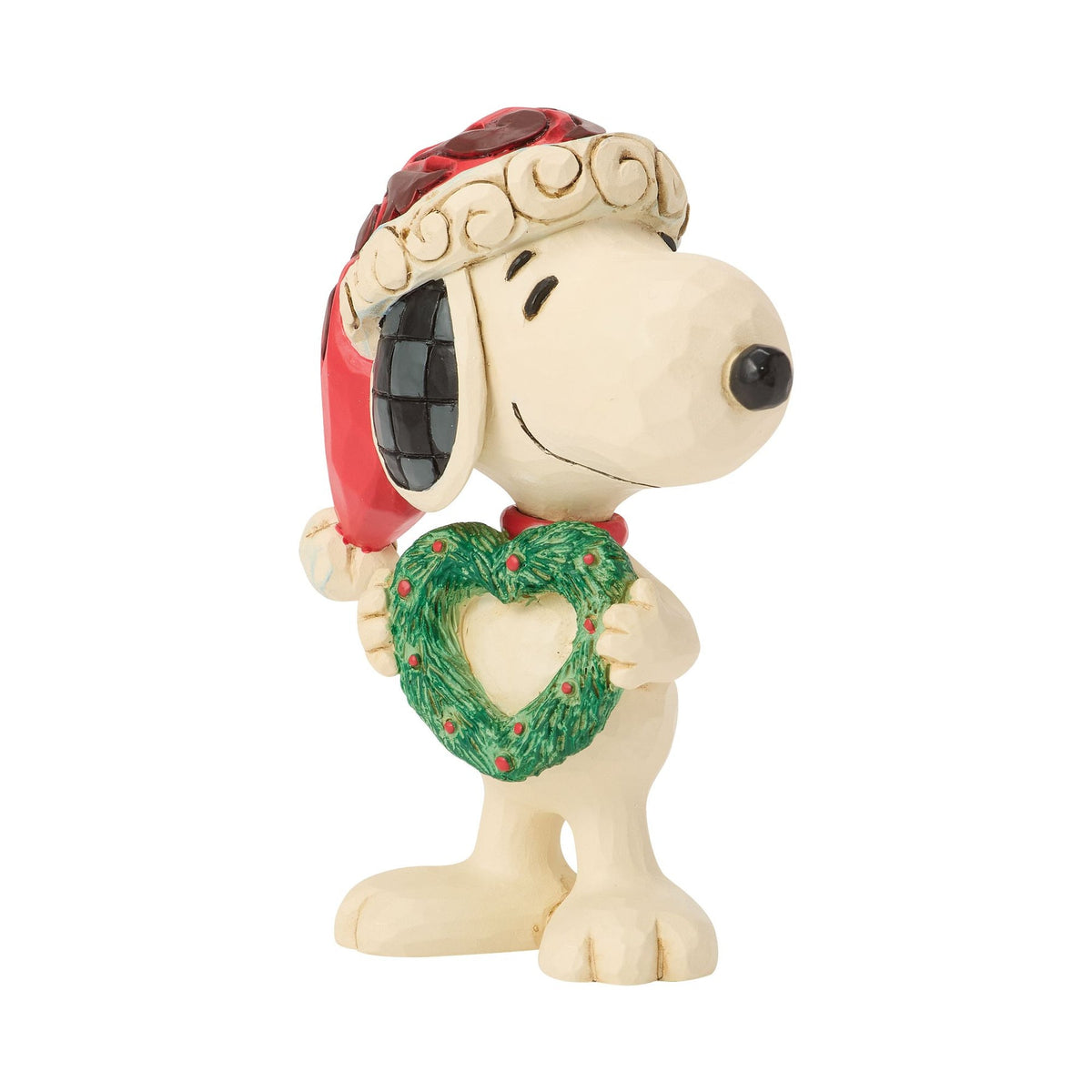 Snoopy Christmas figurine, right front angle, red scrollwork Santa hat with pompom, holding green heart-shaped wreath with red dots