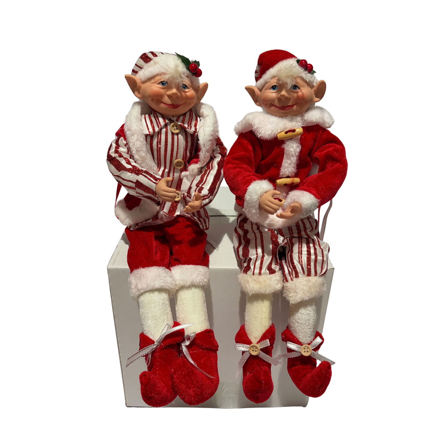 Two Christmas elves in red and white outfits on a white box.