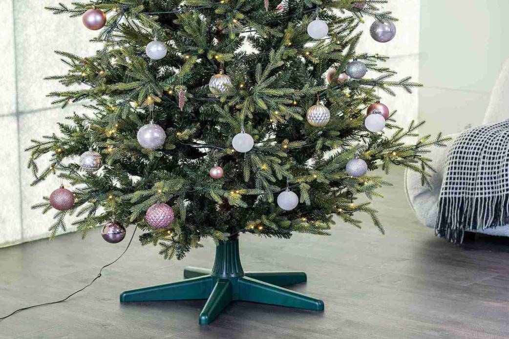 Green rotating tree stand with star base shown supporting a decorated Christmas tree
