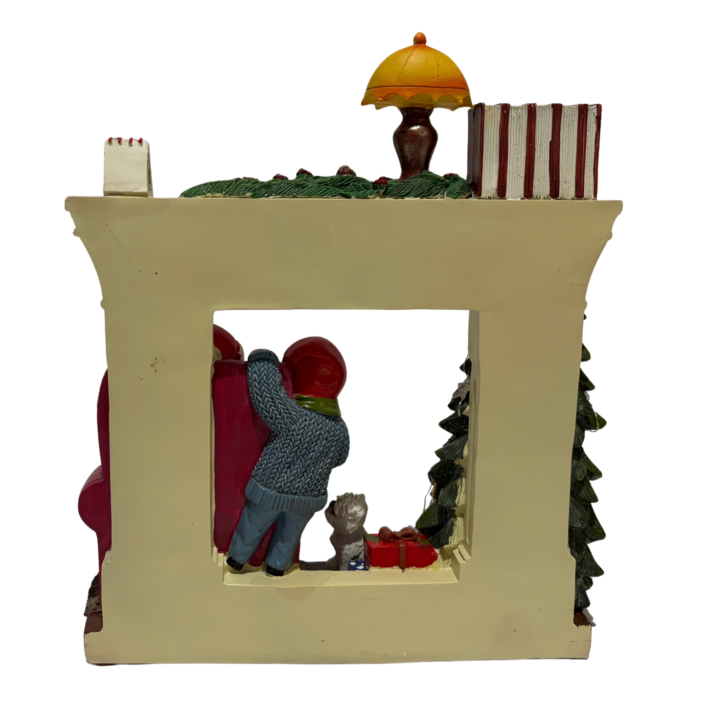 Santa sitting in an armchair beside a Christmas tree and fireplace with a child and dog nearby