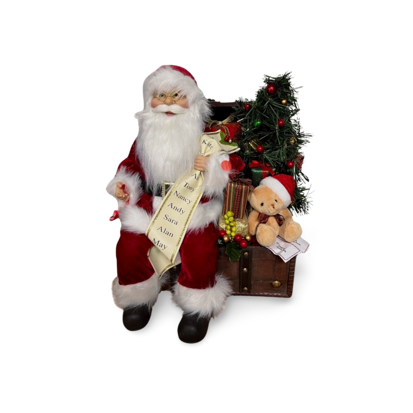 Santa Claus figurine sitting on a chest, holding a list, with a decorated Christmas tree, presents, and a teddy bear in a Santa hat.