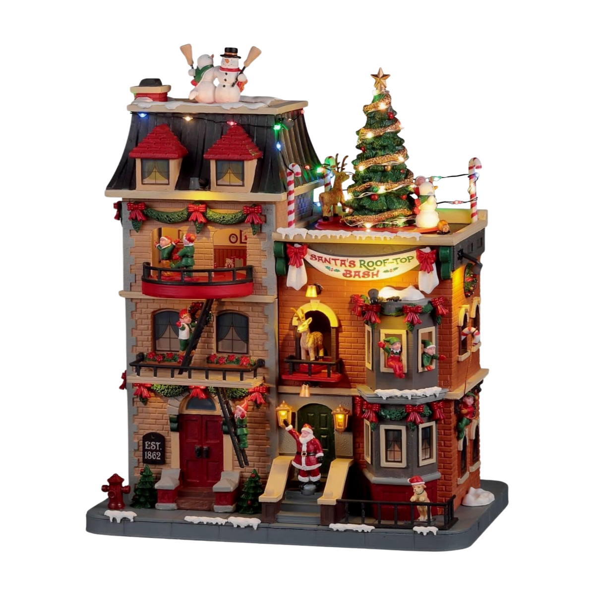 Illuminated multi-storey Christmas village building with Santa's Rooftop Bash sign, decorated tree, elves, snowmen, and reindeer
