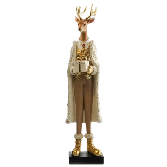 A decorative Christmas tree figurine shaped like a stag deer dressed in a long cream lace-trimmed cape, brown suit, and gold boots, holding a gift box on a black base against a white background.