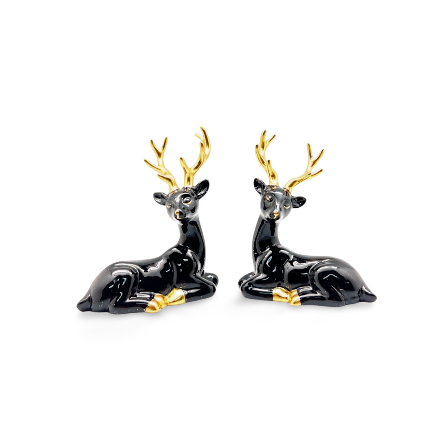 Glossy black ceramic reindeer figurine in a reclining pose with gold antlers, hooves, and nose.