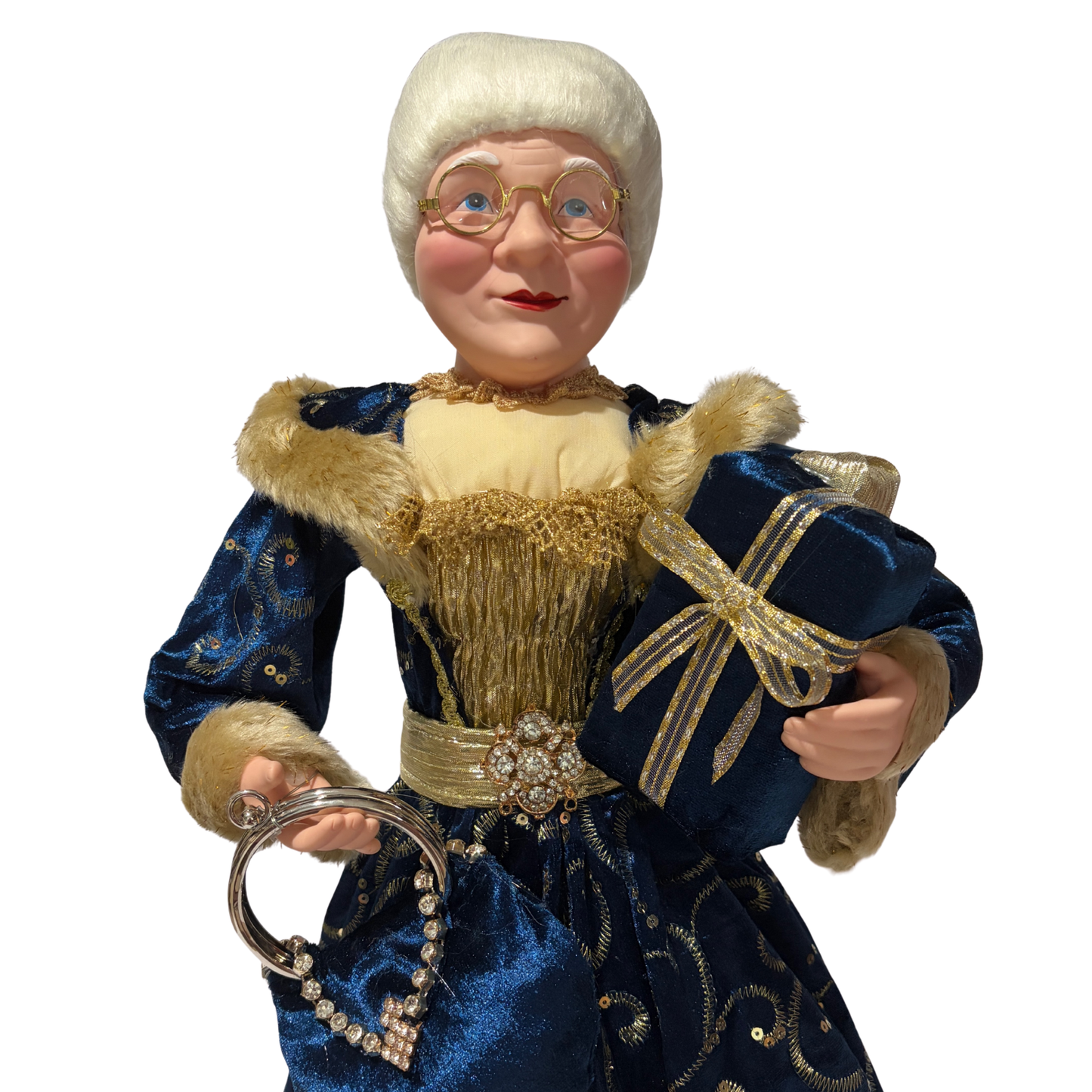  Mrs Claus wearing a blue dress with gold accents, holding two presents in one hand and a blue handbag in the other