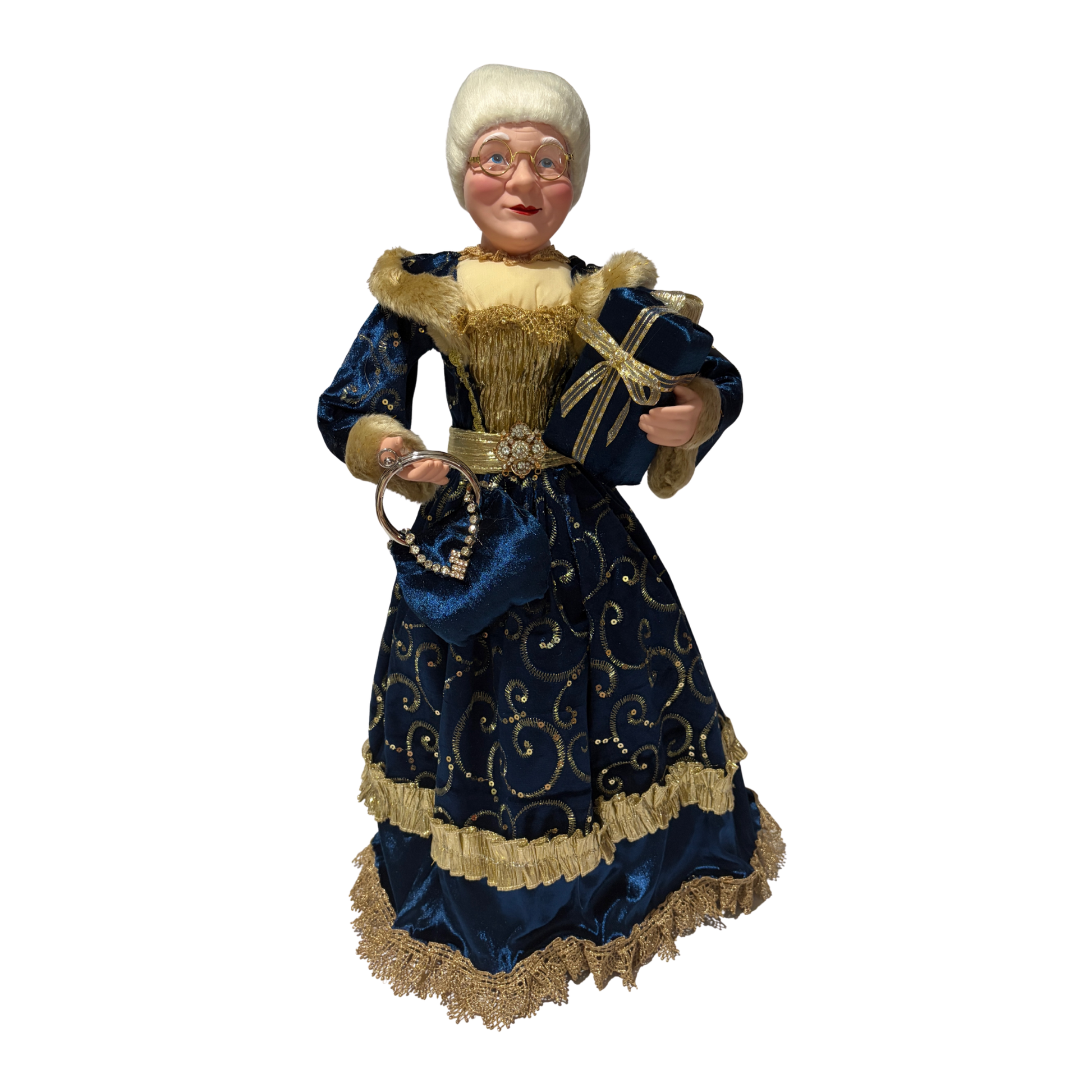 Mrs Claus wearing a blue dress with gold accents, holding two presents in one hand and a blue handbag in the other