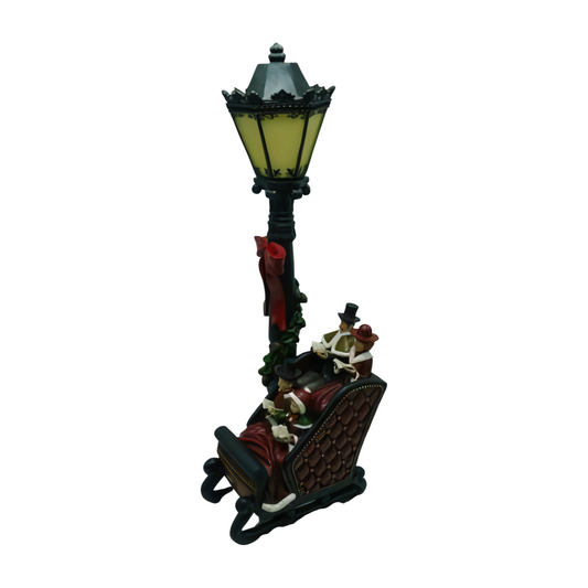Carollers in a sleigh beside a glowing lamppost decorated with holly and a red ribbon