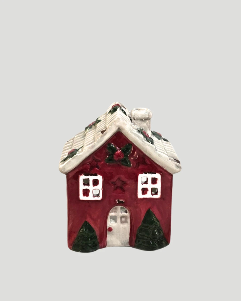 Ceramic red house tea light holder with snow-dusted roof on plain background