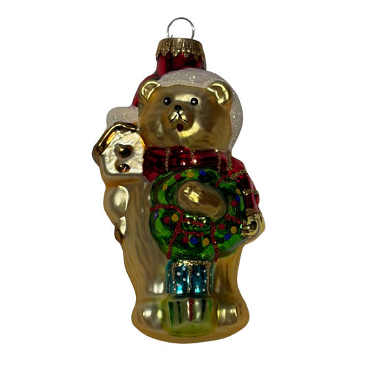 Christmas bear tree decoration wearing a red Santa hat and scarf, holding a green wreath