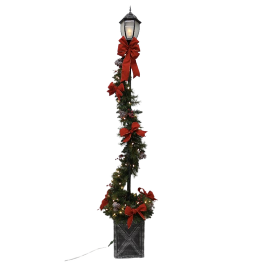 Decorative Christmas lamp post with red bows and lights on a white background