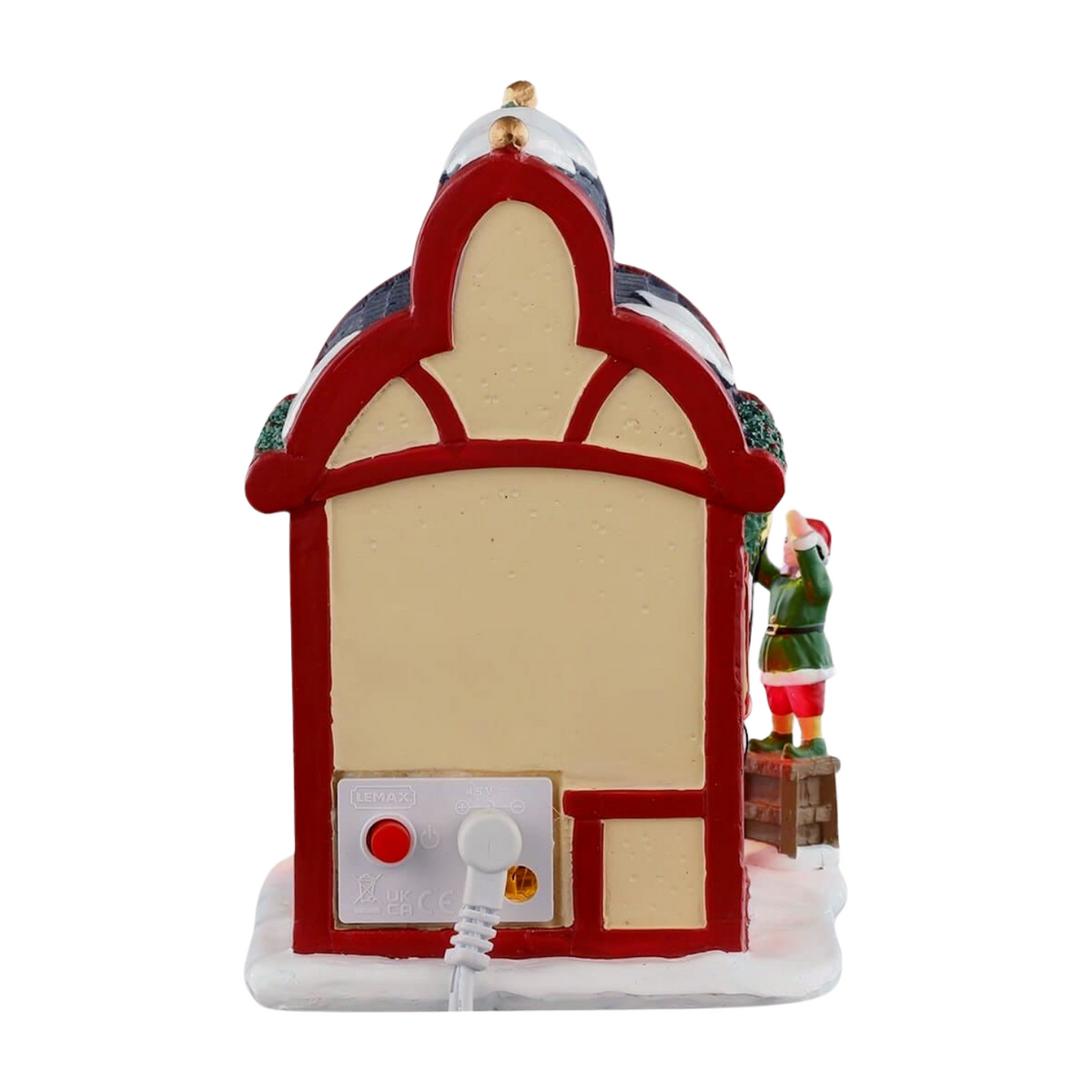 Rear of Comet's reindeer stable village building with red arched facade, slate roof, elf figurine on a crate, and power connector at base