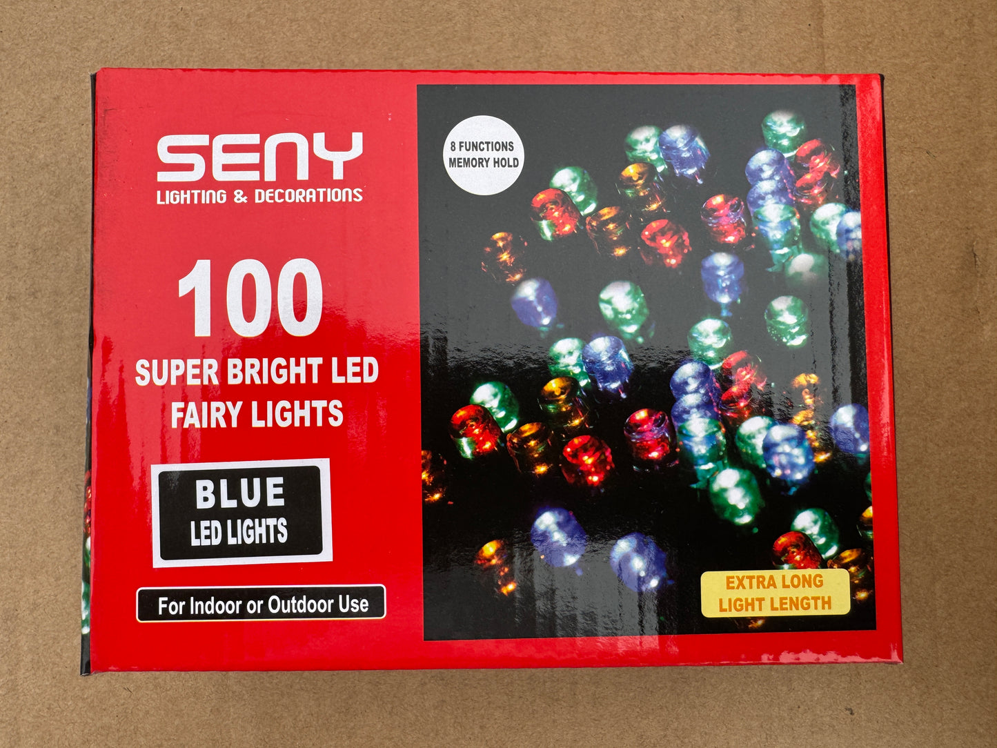 Box of SENY 100 Super Bright LED Fairy Lights with blue LED lights on a brown background