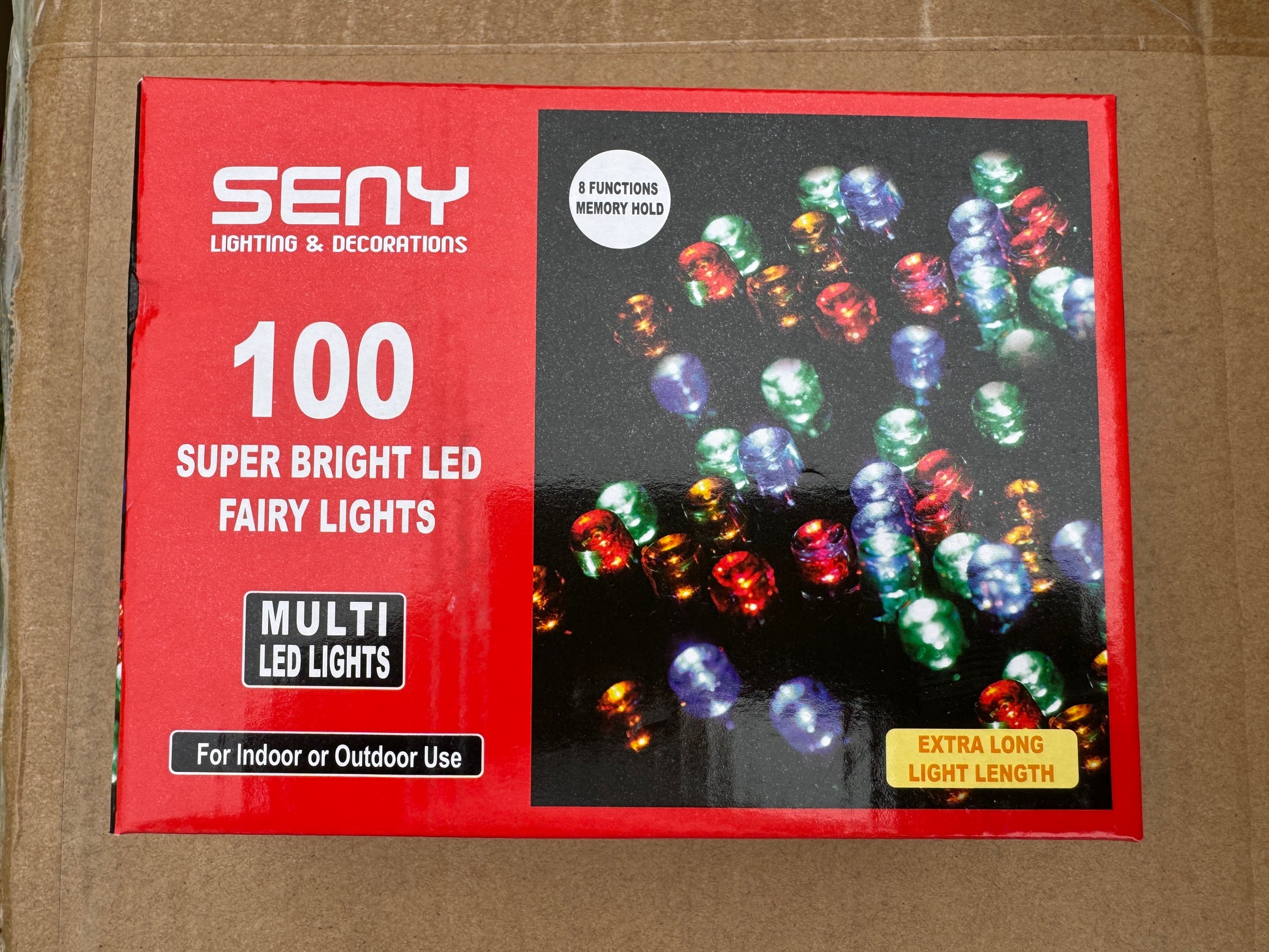 Box of SENY LED fairy lights with colorful bulbs on a brown background