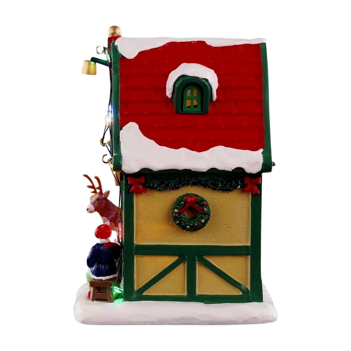Left view of Cupid's reindeer stable village building showing red roof, timber-framed walls, wreath, and reindeer figurine peeking out