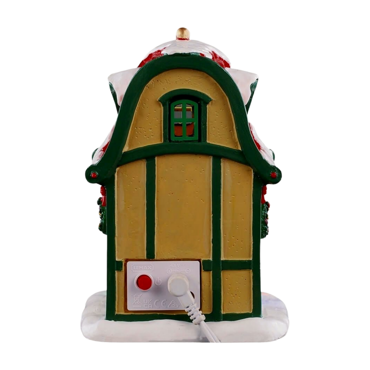 Rear of Cupid's reindeer stable village building with arched green-trimmed facade, lit window, and power connector at base