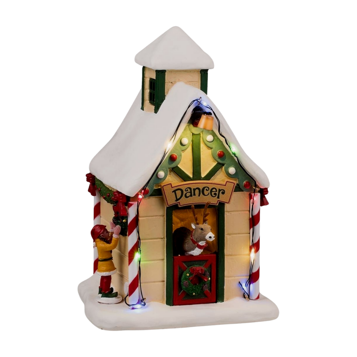 Front view of Dancer's reindeer stable village building with lit tree-shaped gable, Dancer sign, reindeer in doorway, and elf figurine