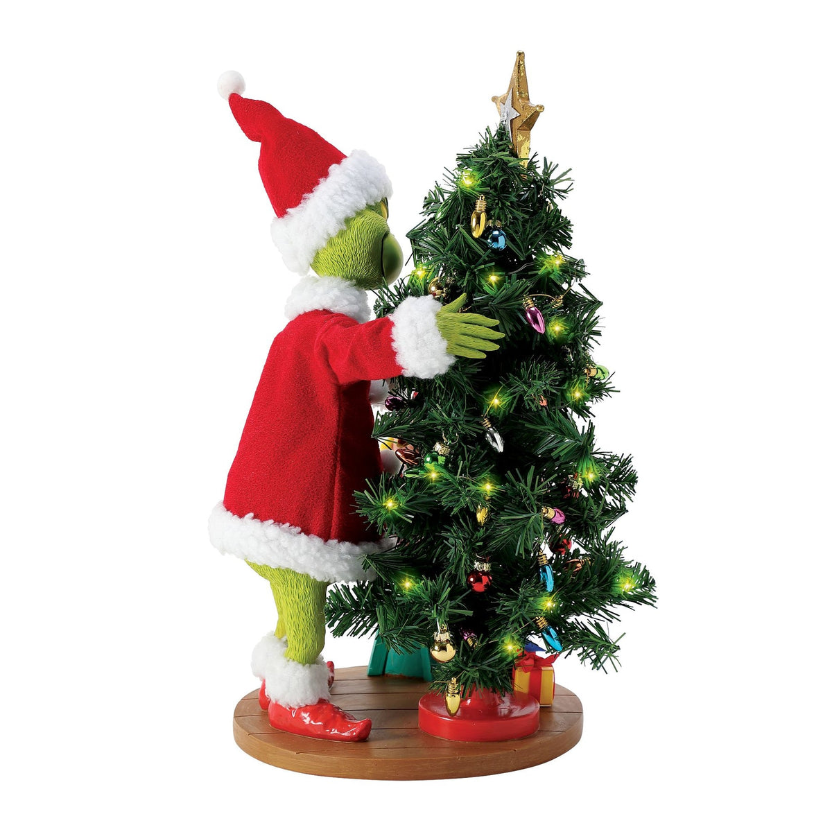 Rear view of the Grinch figurine in a Santa suit embracing a lit, decorated Christmas tree with colourful ornaments and a star topper