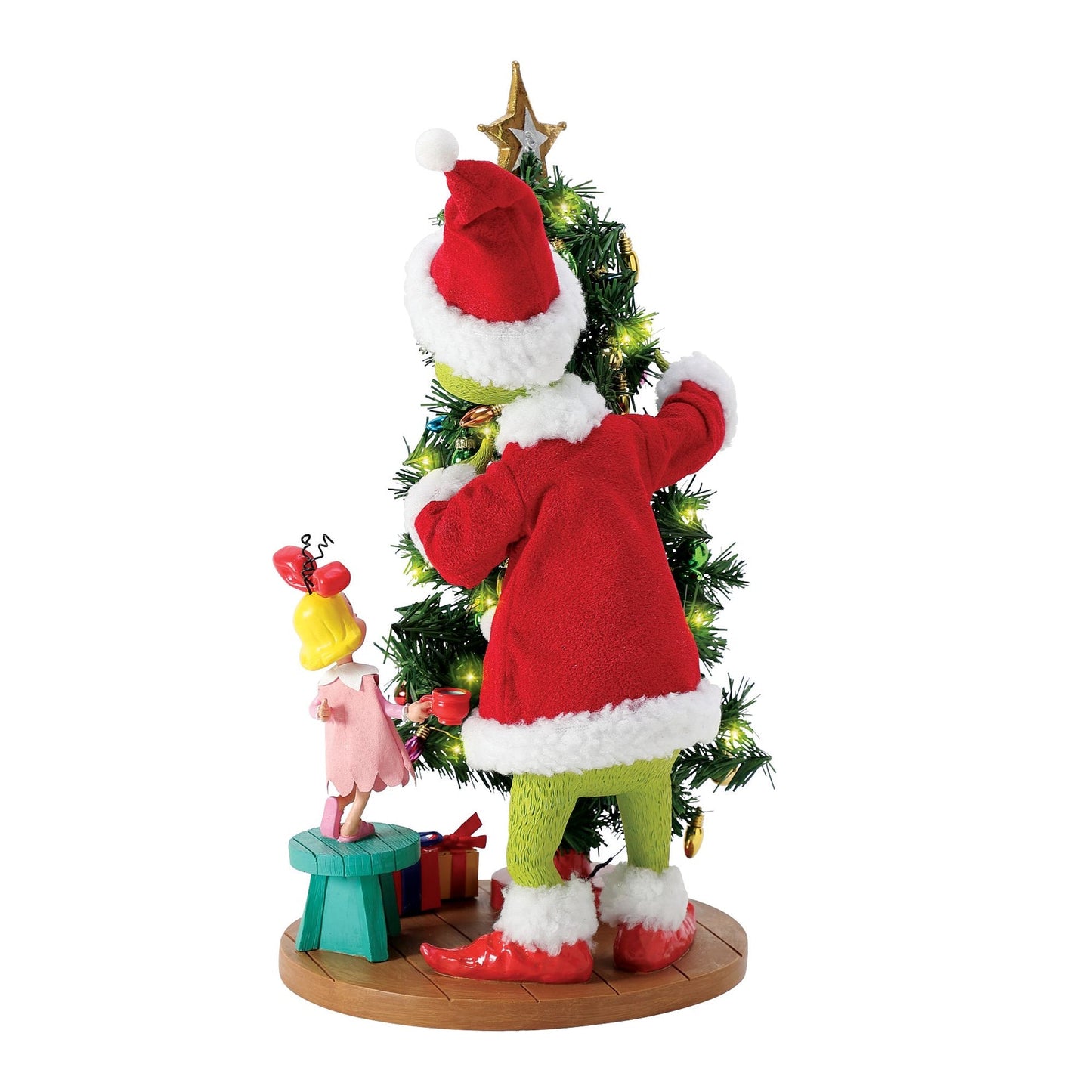 The Grinch in a Santa suit clutching a lit decorated Christmas tree, Cindy Lou Who figurine beside him on a stool, gifts on the base 