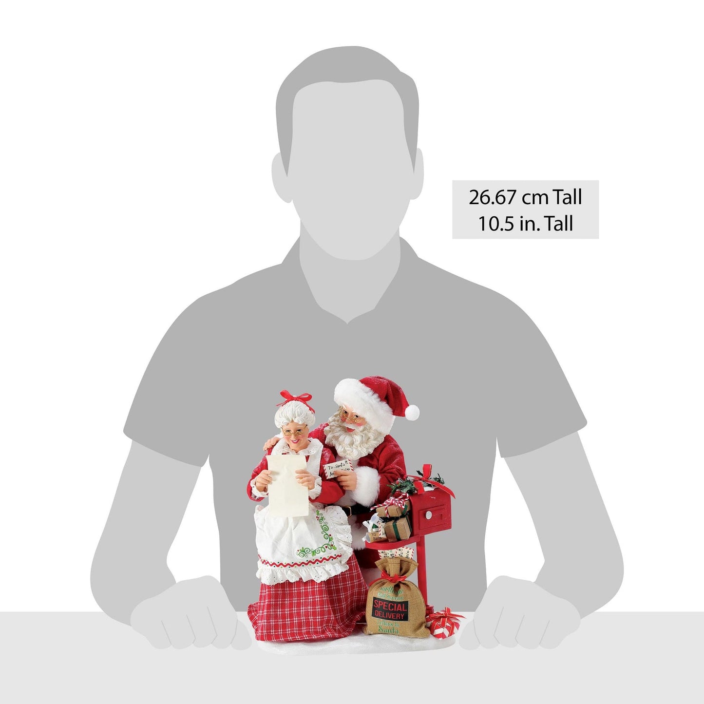 Santa and Mrs. Claus figurines reading mail at a red letterbox shown against a human silhouette for scale, 26.67 cm / 10.5 inches tall