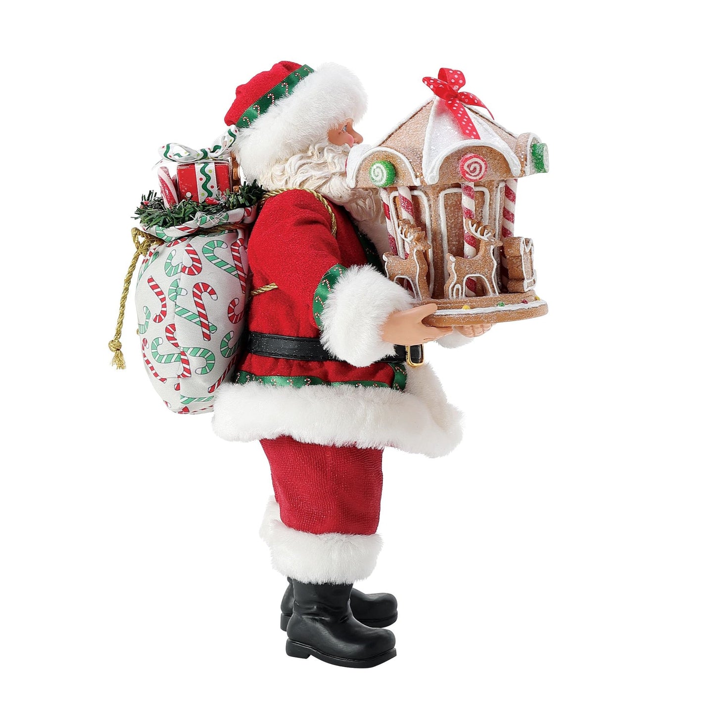 Side view of Santa figurine holding a gingerbread carousel with reindeer detail, candy cane–printed gift sack on his back