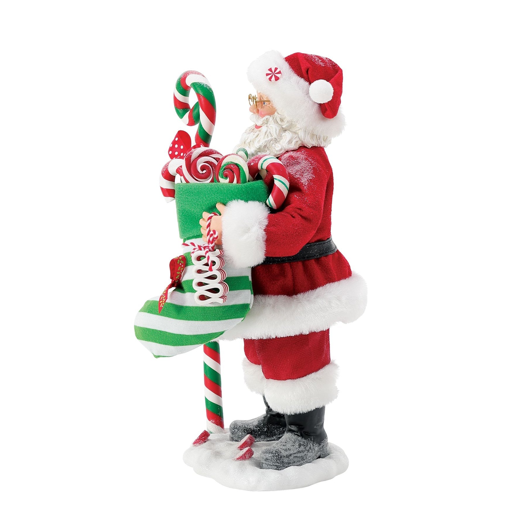 Side view of Santa figurine in red suit, striped candy cane staff and candy-filled stocking visible either side, snowy base