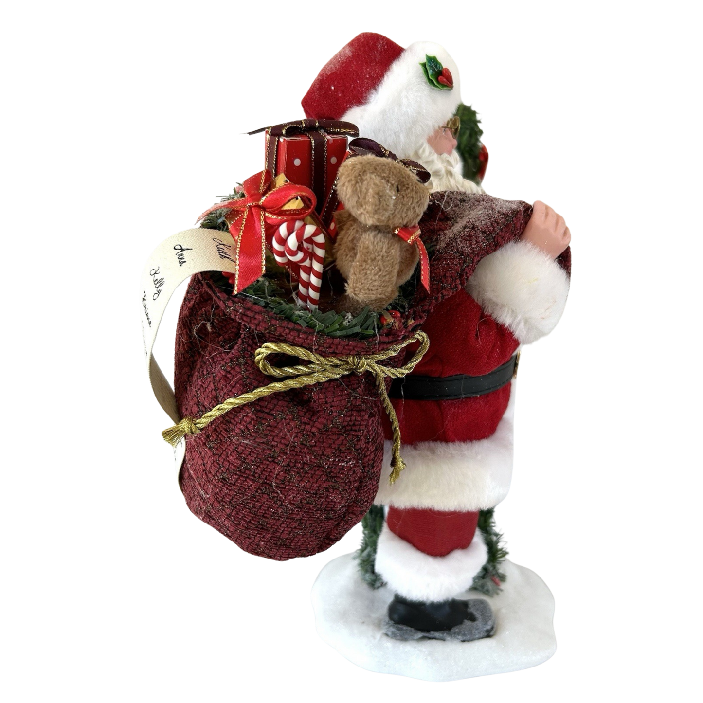 Close detail of Santa's overflowing burgundy gift sack containing a teddy bear, candy canes, wrapped presents, and a handwritten name list