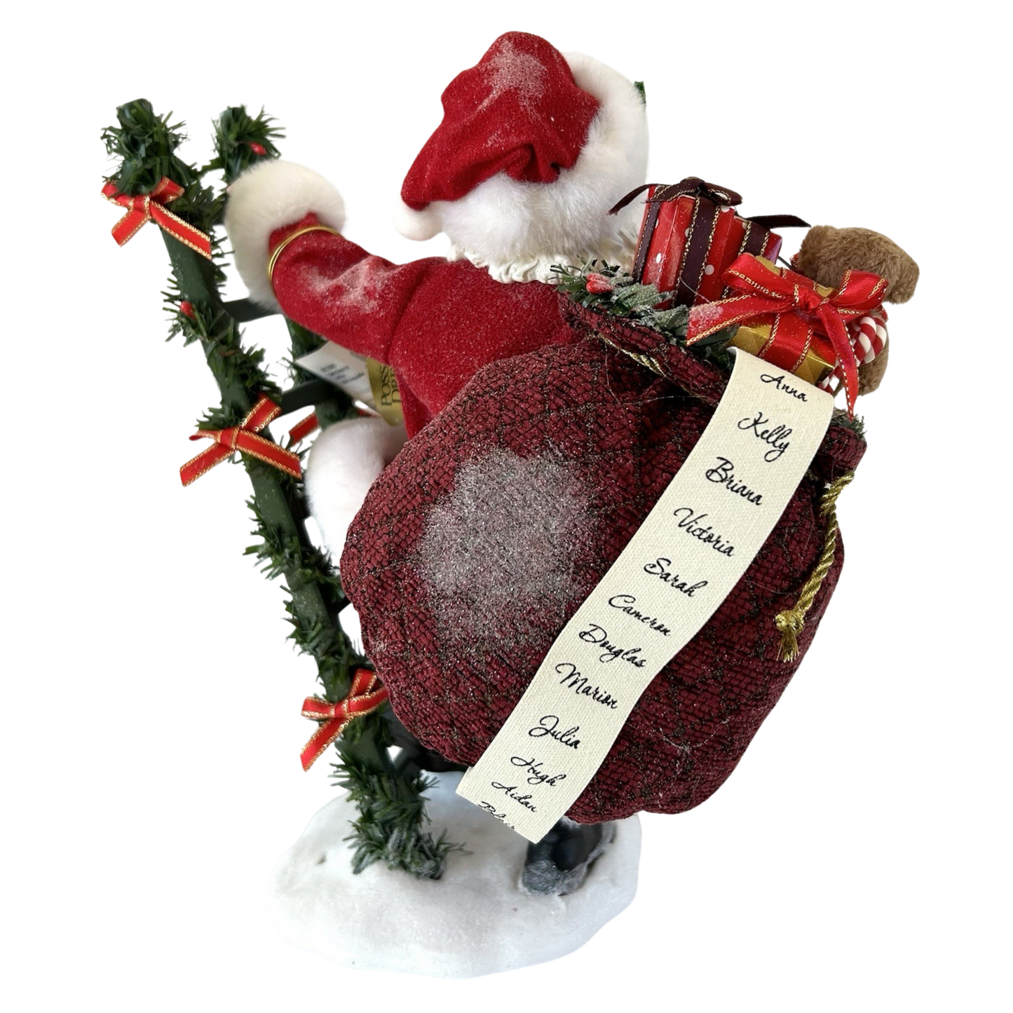 Back view of a Santa figure carrying a gift-filled burgundy sack with a handwritten naughty-and-nice list, beside a garland-wrapped ladder