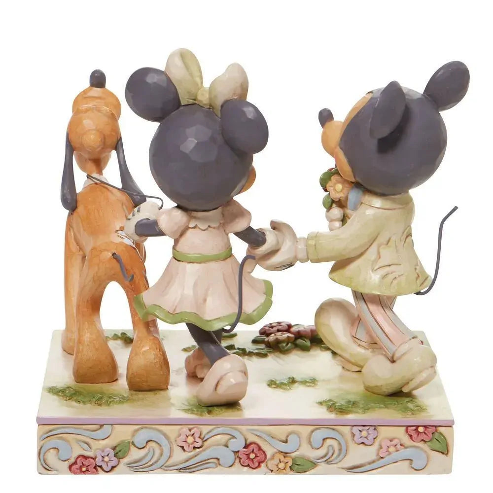 Disney Traditions figurine of Mickey and Minnie Mouse holding hands with Pluto, in pastel spring colours on a floral base