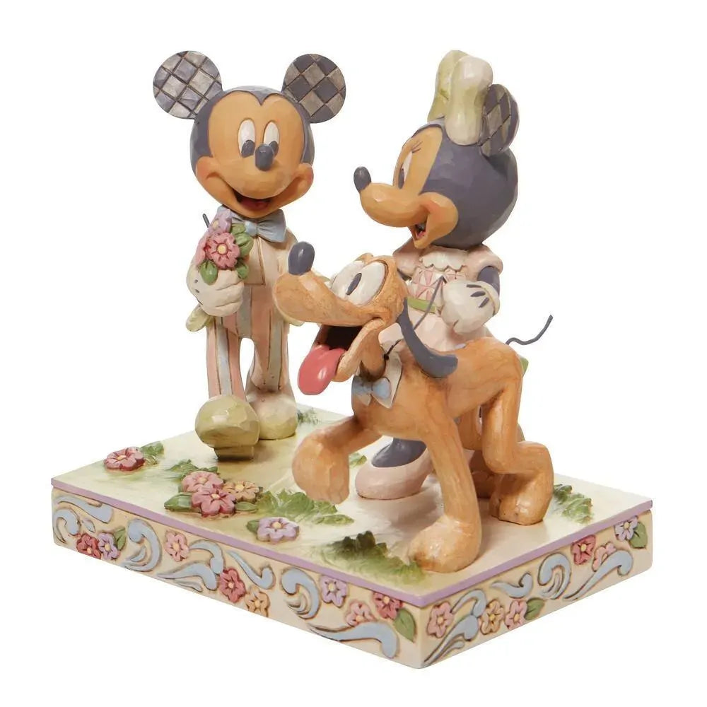 Disney Traditions figurine of Mickey and Minnie Mouse holding hands with Pluto, in pastel spring colours on a floral base