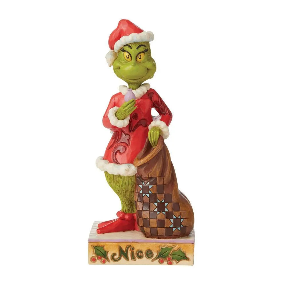 Opposite side of Grinch figurine in red folk art Santa suit holding an ornament beside a patchwork sack, "Nice" inscribed holly base