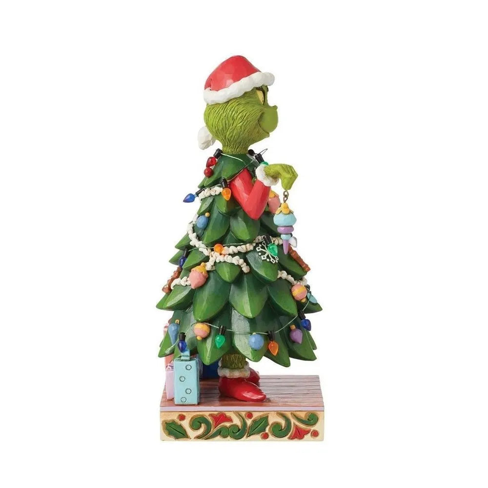 Side view of a Grinch figurine dressed as a decorated Christmas tree with colourful ornaments, lights, and gifts at his feet
