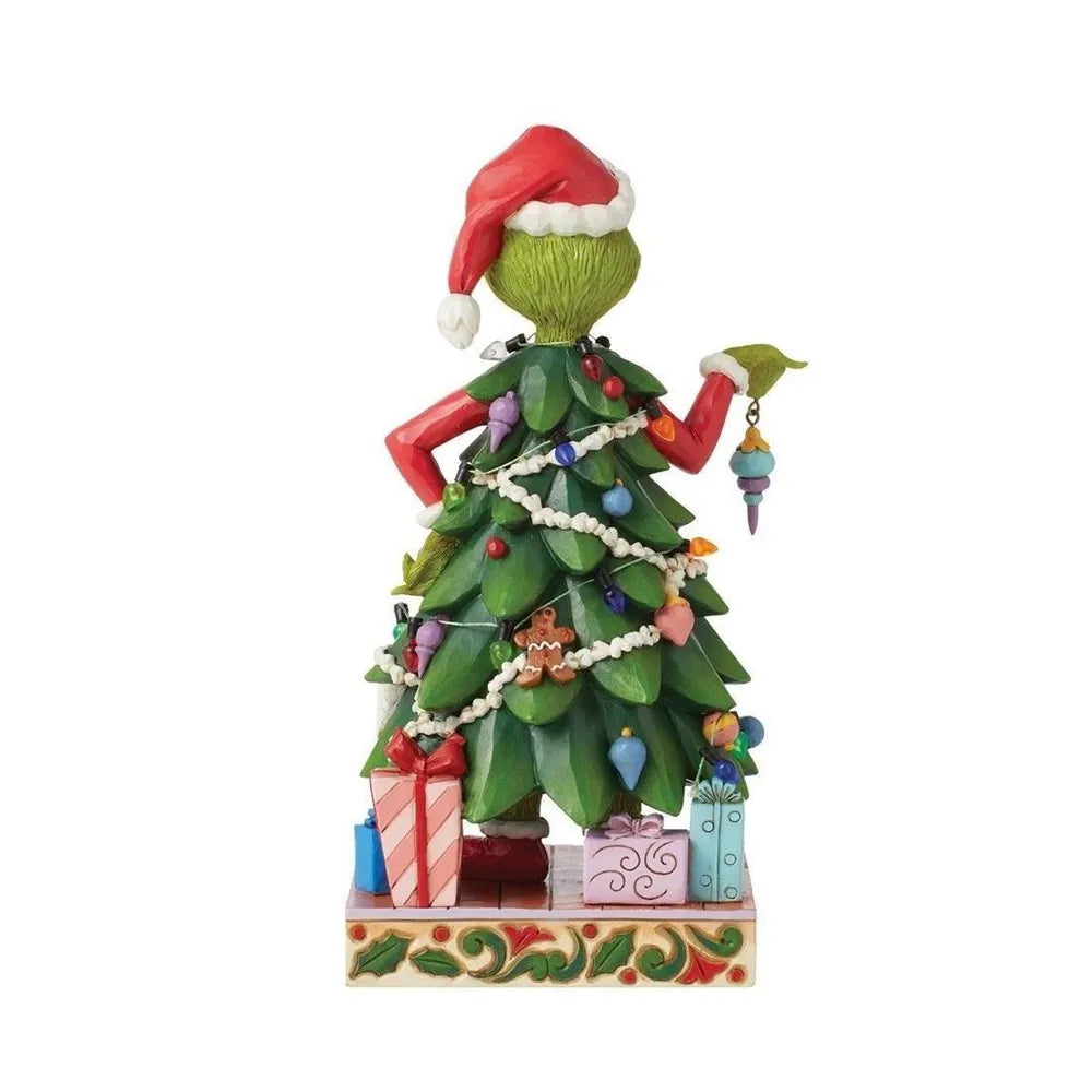 Rear view of a Grinch Christmas tree figurine holding a bauble, with wrapped gifts and a holly-detailed scrollwork base.