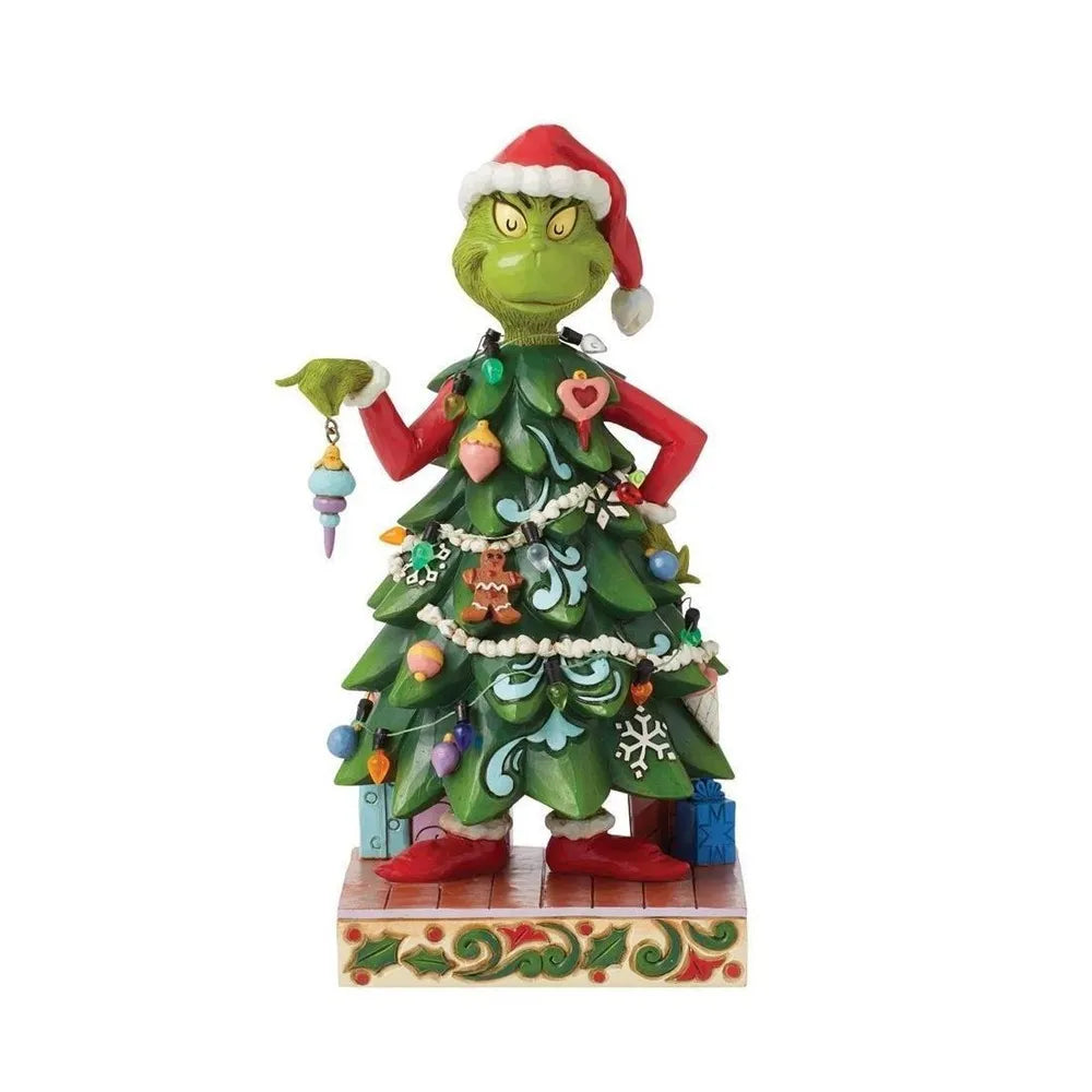 Front view of a Grinch figurine wearing a Christmas tree costume covered in ornaments and garland, holding a bauble with a scowl