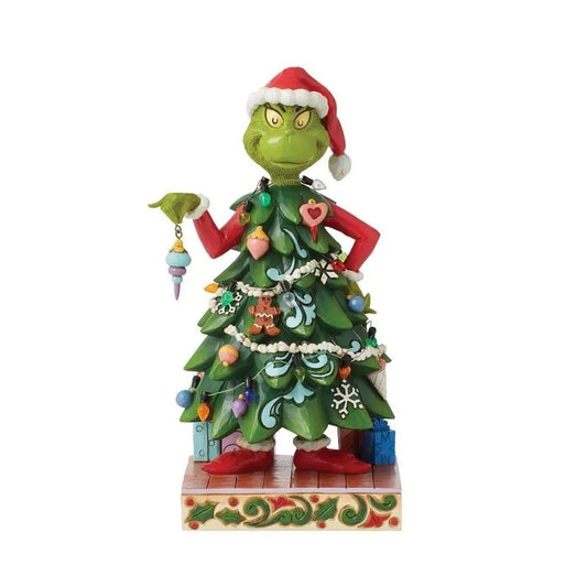 Front view of a Grinch figurine wearing a Christmas tree costume covered in ornaments and garland, holding a bauble with a scowl