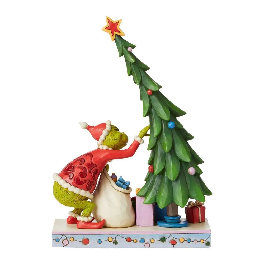Left side view of Grinch figurine in red Santa suit stealing decorations from a Christmas tree, gift sack at his feet