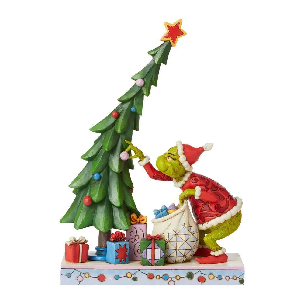 Right side view of Grinch figurine in red folk art Santa suit stripping a decorated Christmas tree, colourful gifts scattered around base
