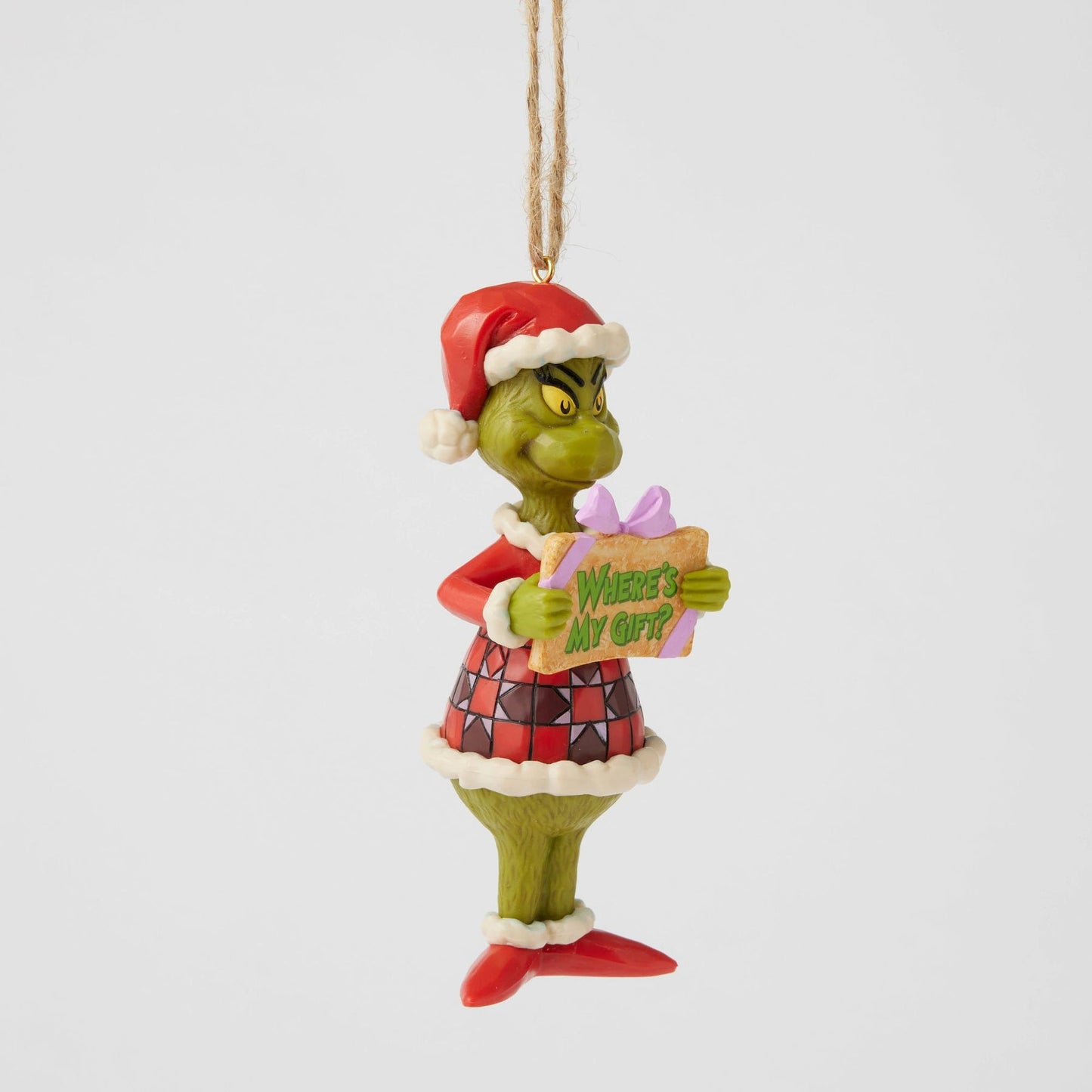 Front view of Grinch ornament wearing Santa hat, holding "Where's My Gift?" sign, red geometric patterned coat, jute cord hanger 