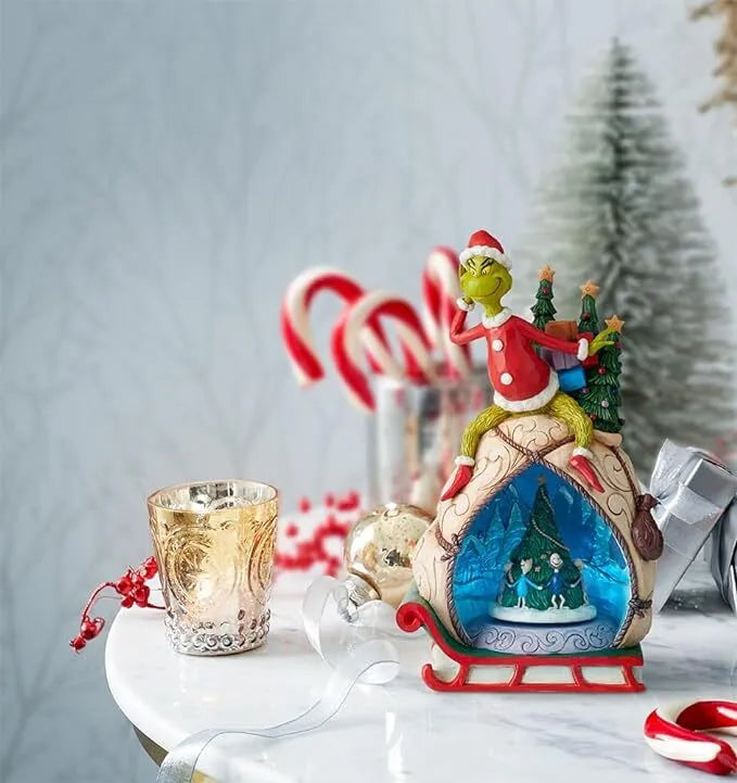 Grinch sleigh figurine styled in a Christmas vignette with candle holder, ornaments and candy canes